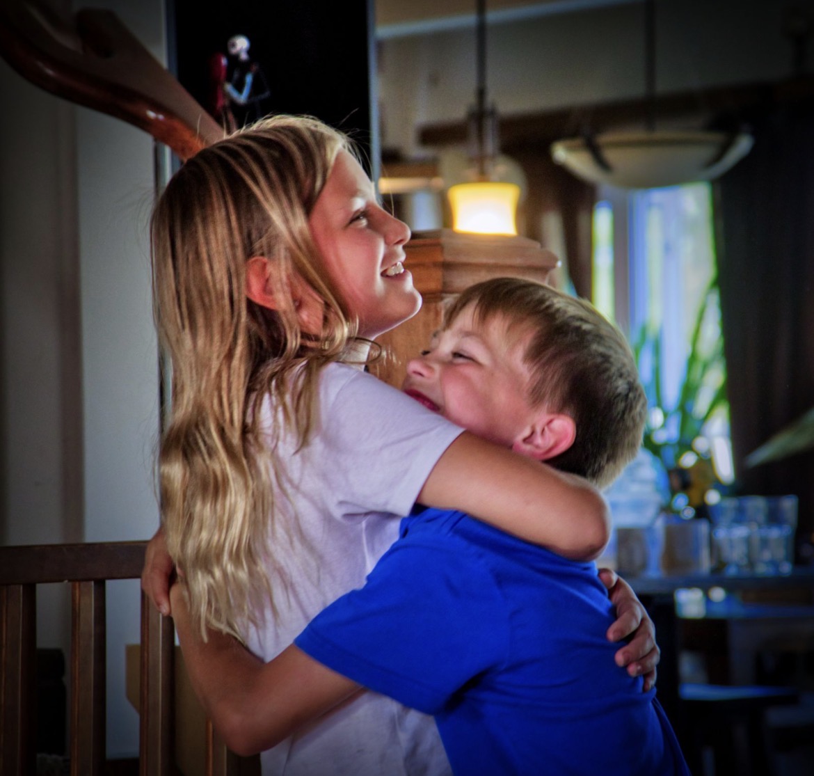 Chantania's daughter and son laughing in a hug at home