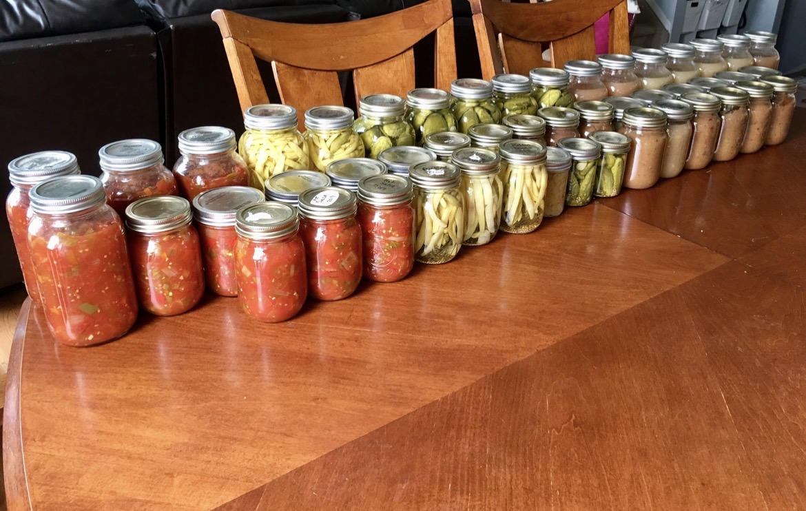 Rows of home-canned tomatoes, beans, pickles and sauce on the table