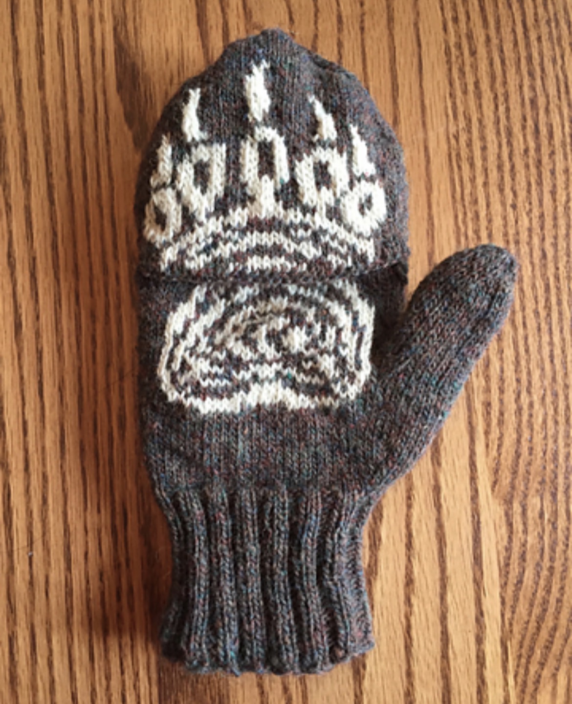 A hand-knit wool mitten with a mountain pattern
