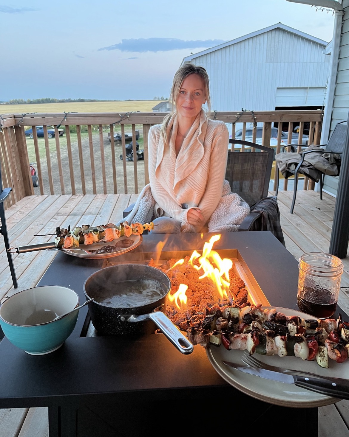 Skewers on the fire table at dusk looking out over the field