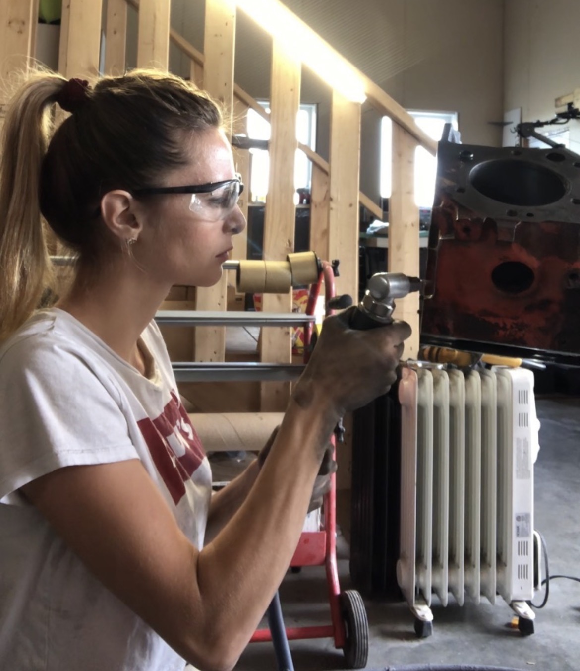 Stripping a bellhousing with a blasting gun in safety glasses